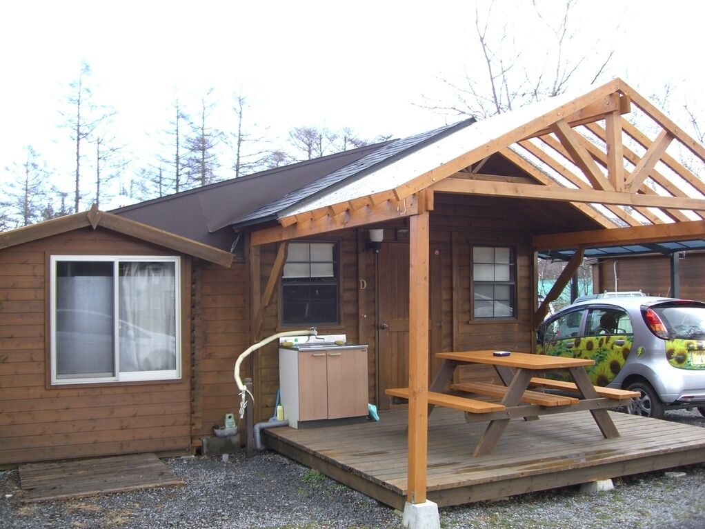 Eine Holzhütte mit überdachter Veranda, einem Spülbecken und einem Picknicktisch.
