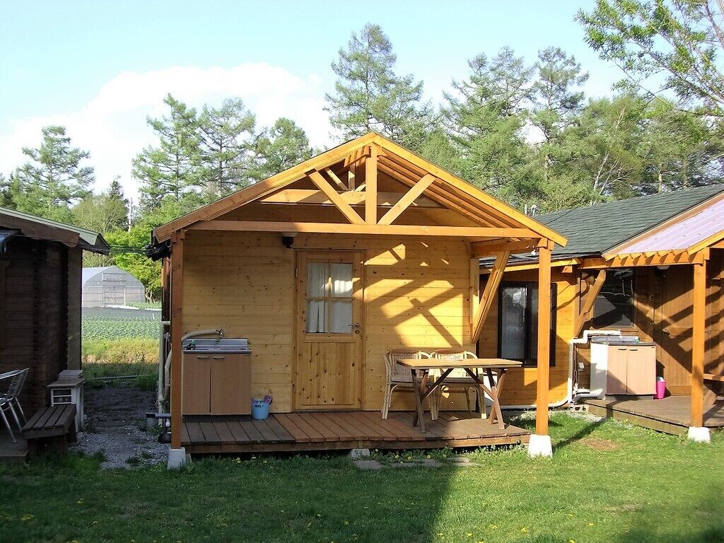Eine Holzhütte mit Veranda, einem kleinen Tisch und einem Fenster.
