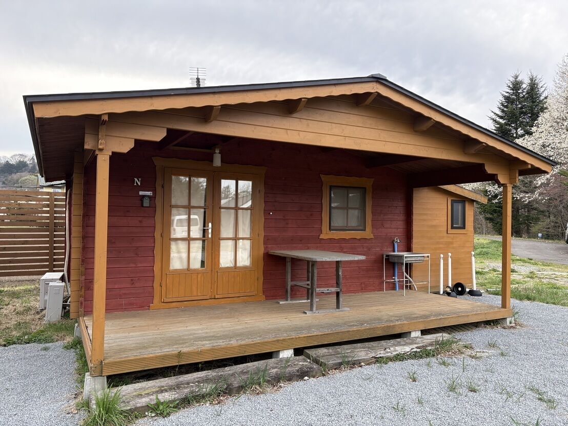 Eine Hütte mit Veranda, Tisch und Stuhl.