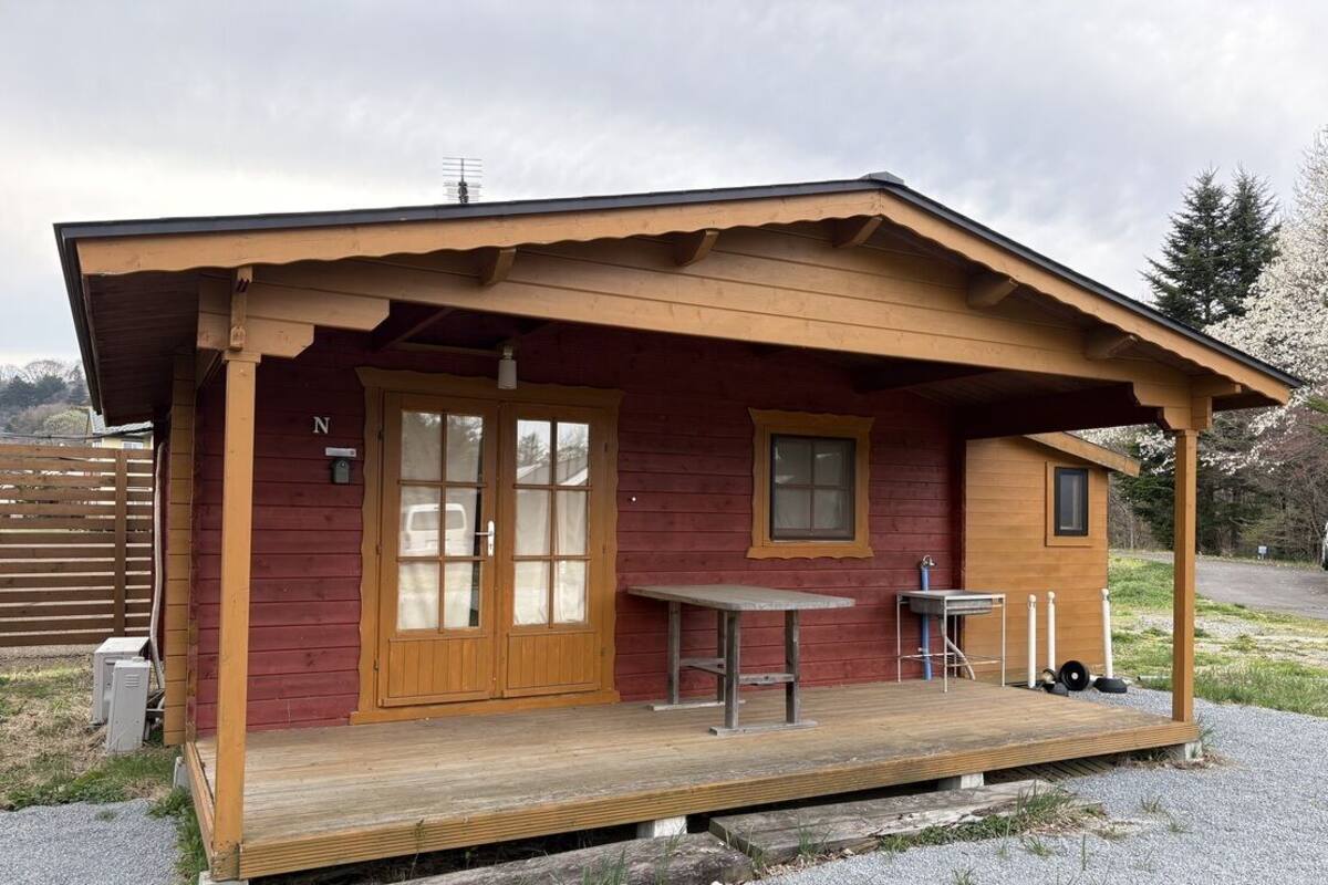 A cabin with a porch, a table, and a chair.