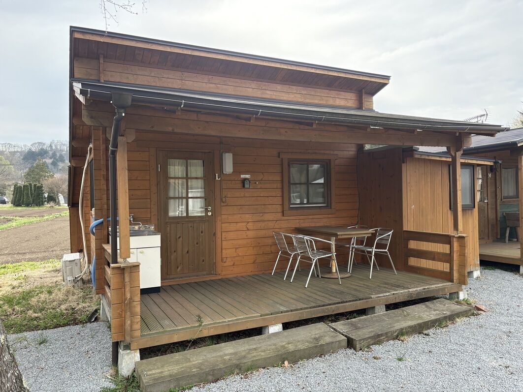 Eine Holzhütte mit einer Veranda, einem kleinen Tisch mit Stühlen und einem Fenster.