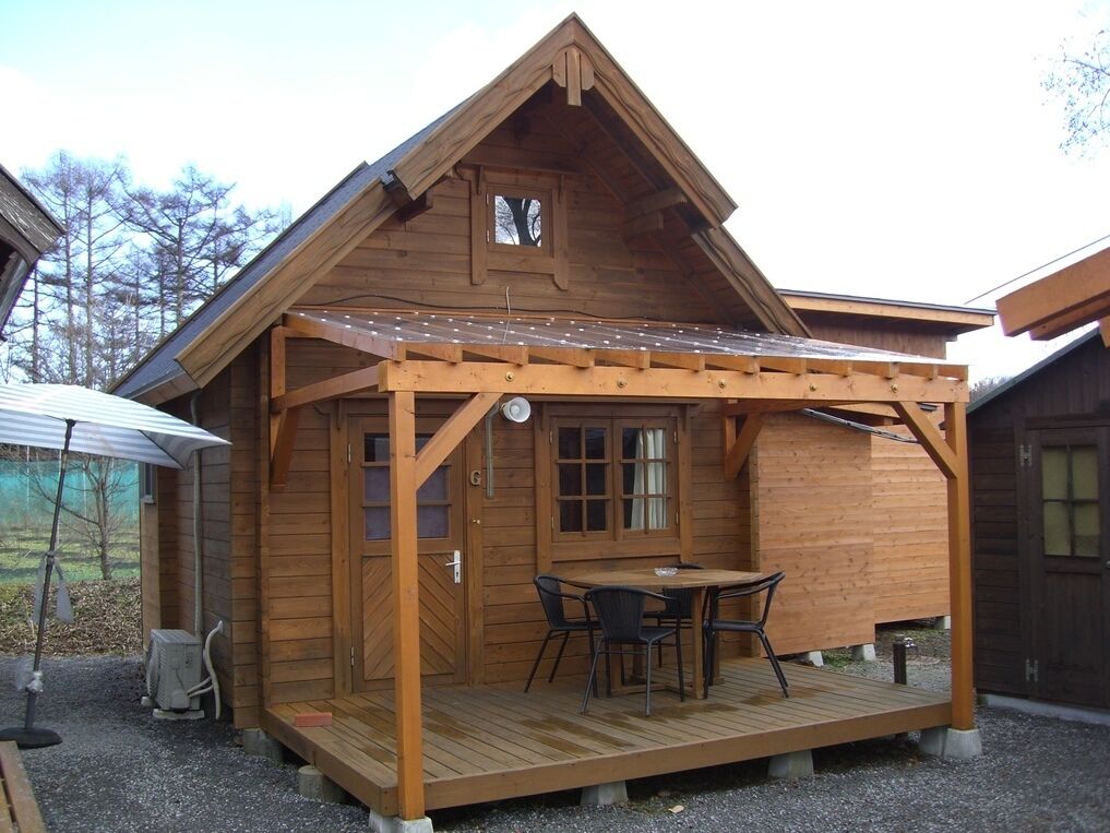 Eine Holzhütte mit Veranda, Tisch und Stühlen.