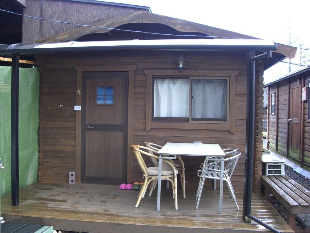 Eine Holzhütte mit überdachter Veranda, einem Tisch und Stühlen.