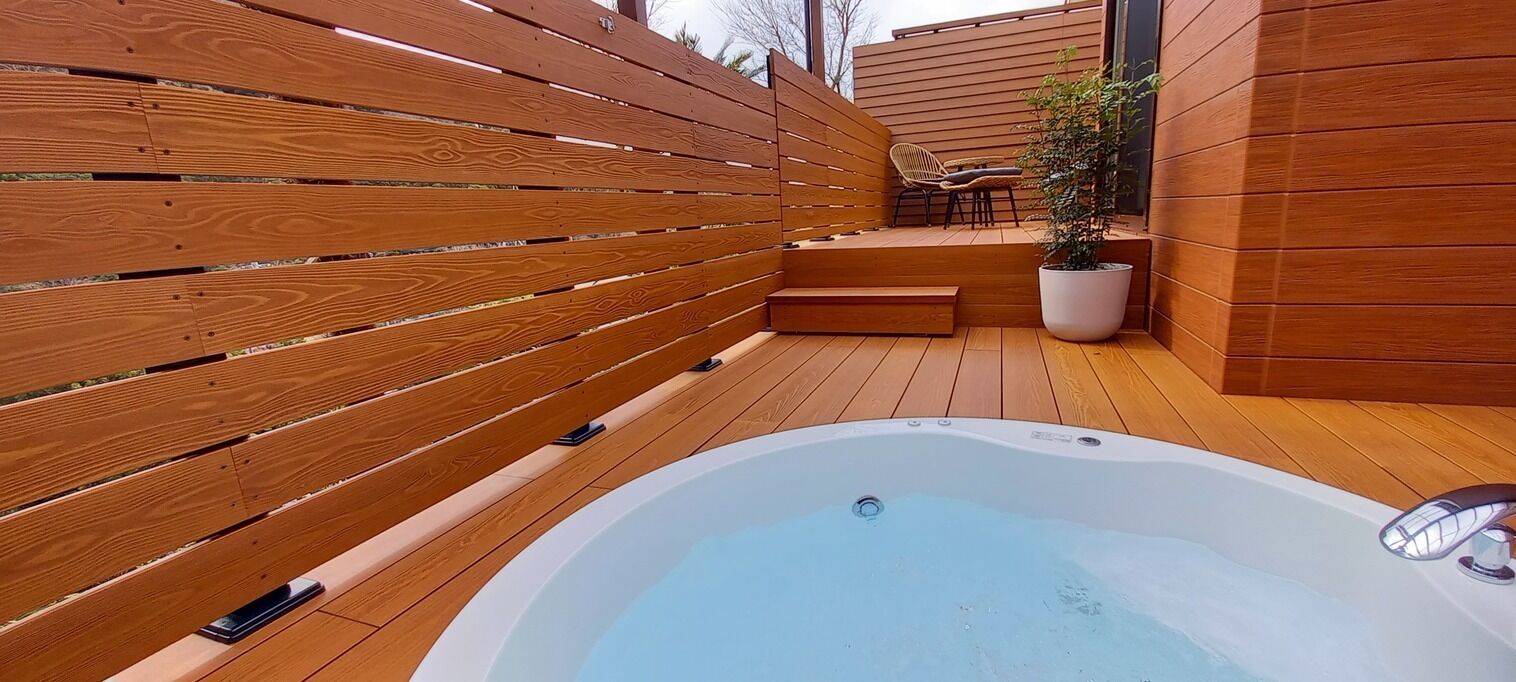 Eine Holzterrasse mit Whirlpool, einem Blumentopf und einer Sitzecke.