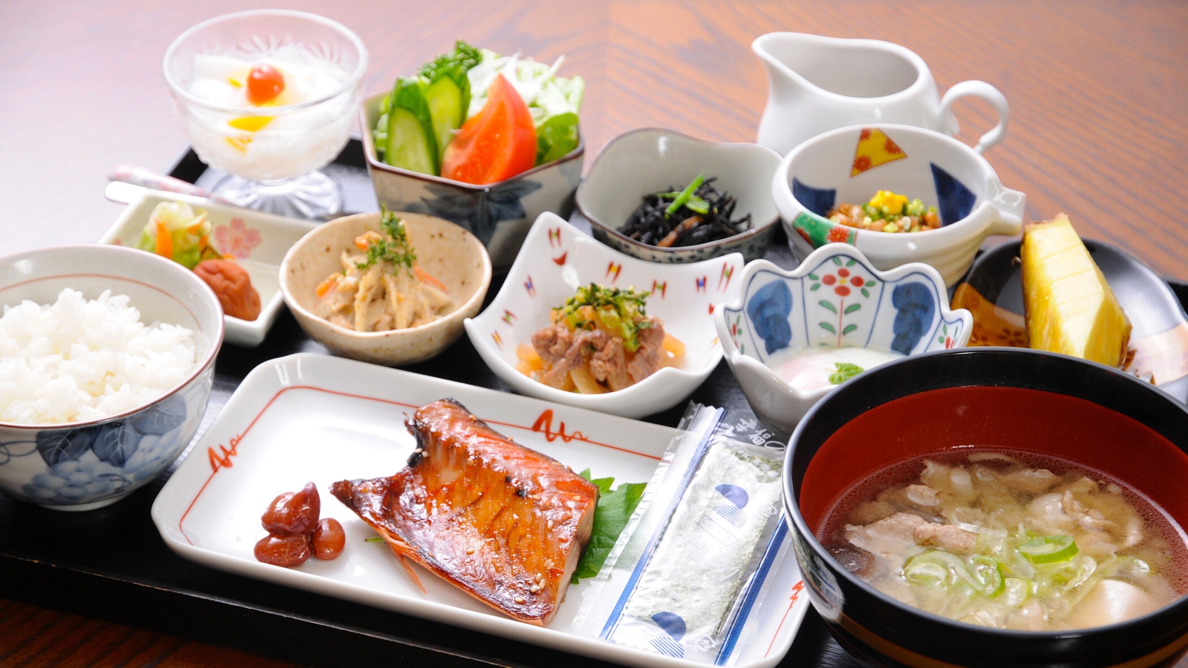 A variety of Japanese dishes including rice, fish, and soup, served on a tray.