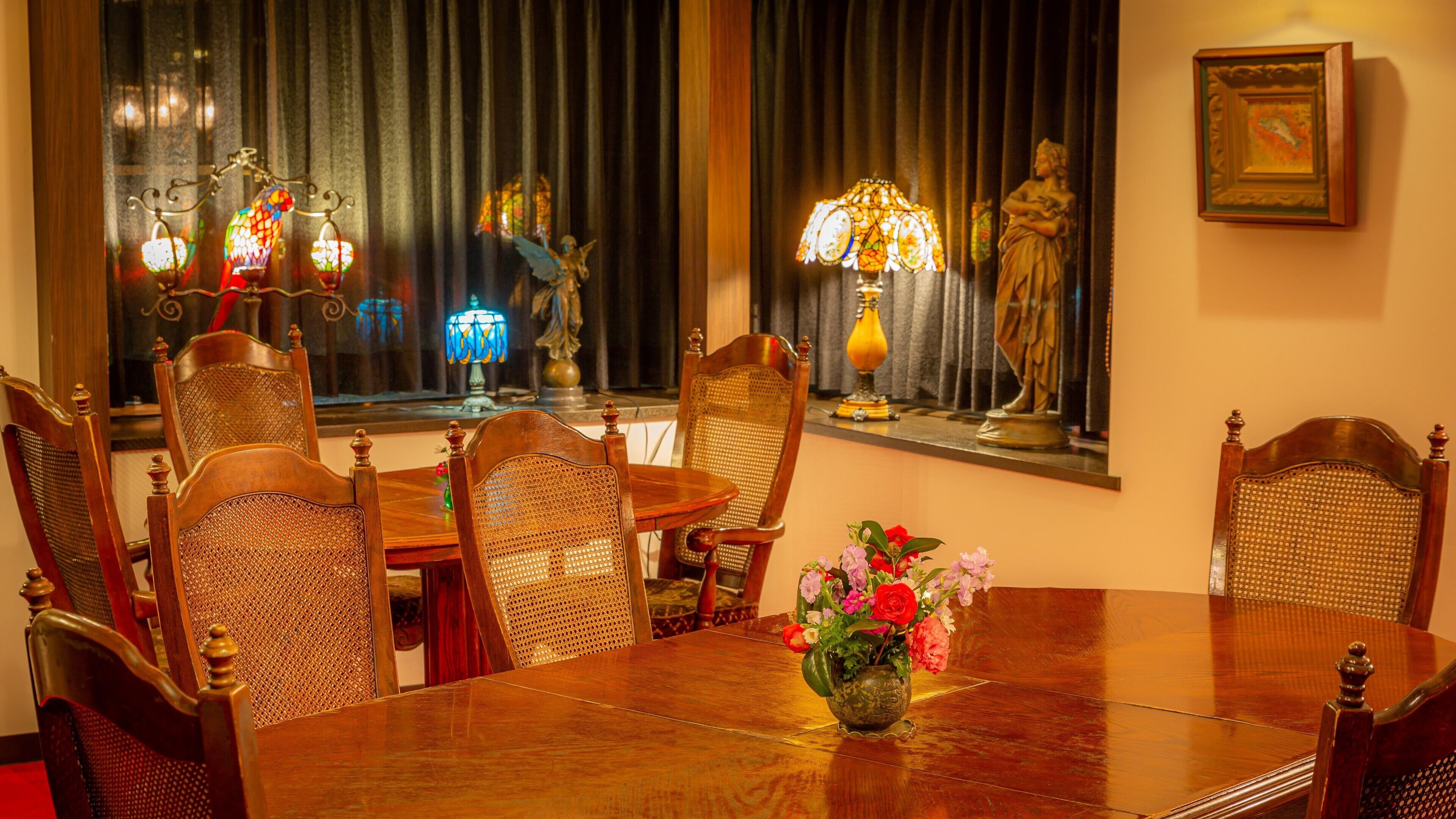 Une salle à manger avec une table en bois, six chaises, un vase de fleurs et des lampes décoratives.