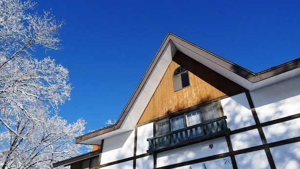 Un bâtiment à l’architecture moderne, caractérisé par une combinaison de panneaux en bois et de panneaux blancs, et doté d’un balcon apparent.