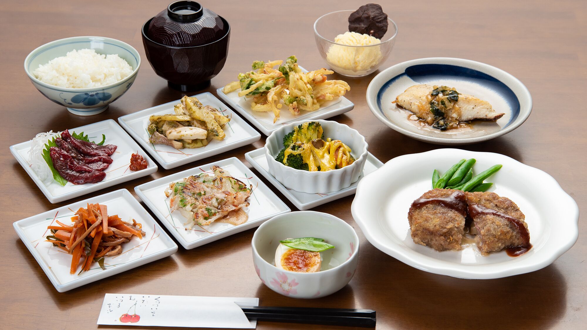 A variety of Japanese dishes arranged on a table, including rice, meat, and vegetables.