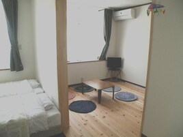 Una habitación con una cama, una mesita, un televisor y una ventana con cortinas.