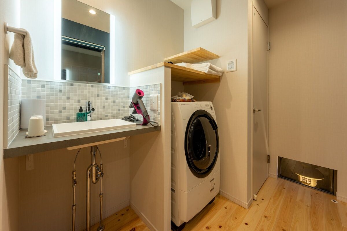 Een kleine keuken met een wasmachine, een spoelbak en een spiegel.