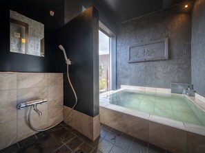 Une salle de bain moderne dotée d’une grande baignoire, d’un espace douche et d’une fenêtre offrant une vue agréable.