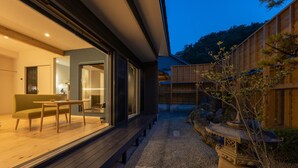A modern house with a wooden deck, a dining area with a table and chairs, and a garden with a stone lantern. - Aone Onsen Itto Onsenyado Seigetsu (Kawasaki)