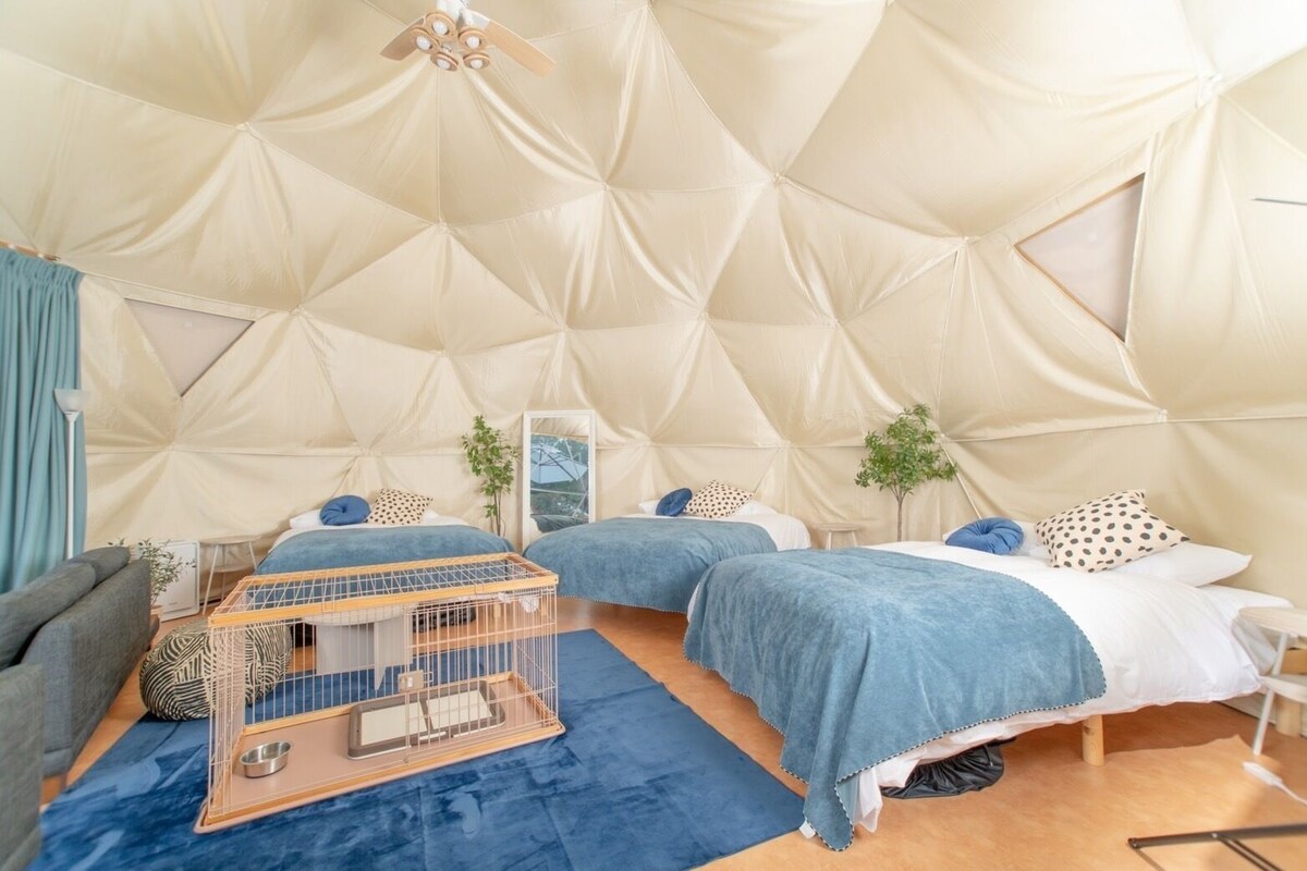 Una stanza a forma di tenda con due letti, una gabbietta per animali e un tavolino.