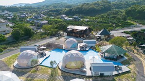 A resort with geodesic dome structures, a swimming pool, and a view of the surrounding residential area. - LIT Shimanami (Onomichi)