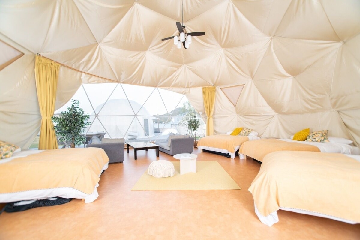 Un'ampia stanza con un design geometrico del soffitto, letti multipli, un divano, un tavolino da caffè e una ventola a soffitto.