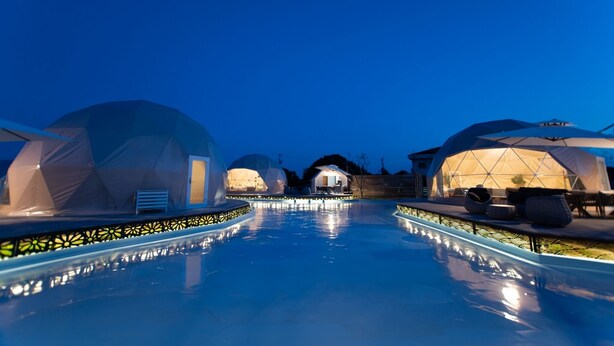 A pool area with dome-shaped structures, likely accommodations, and a clear sky. - LIT Shimanami (Onomichi)