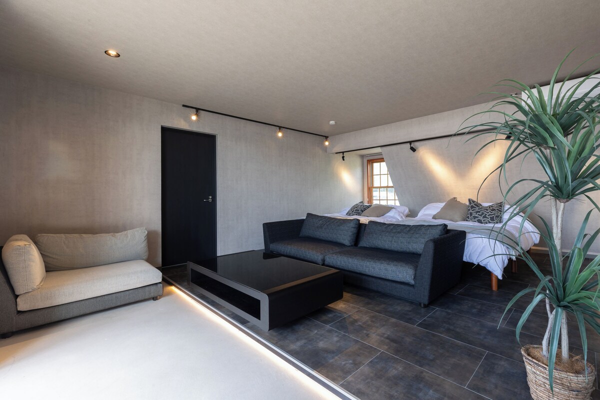 Un soggiorno moderno con un divano, un tavolino e un letto con un comodino.