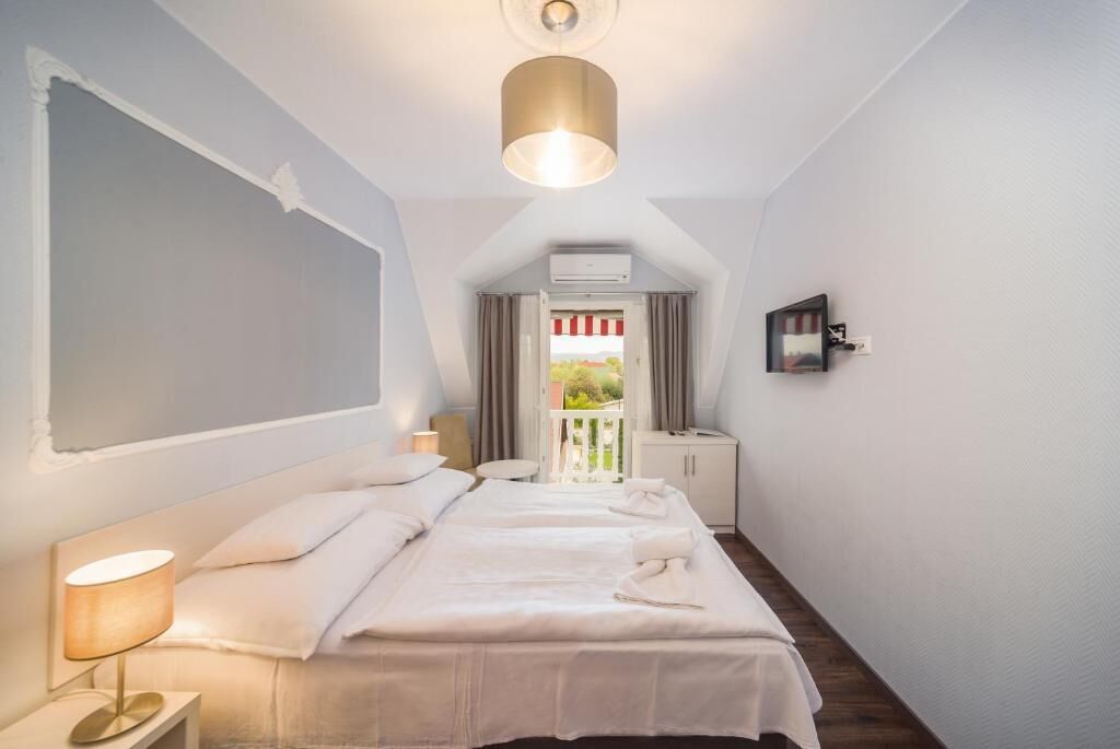 Un dormitorio con dos camas, una lámpara de noche, una luz de techo, una ventana con cortinas y vistas al exterior.