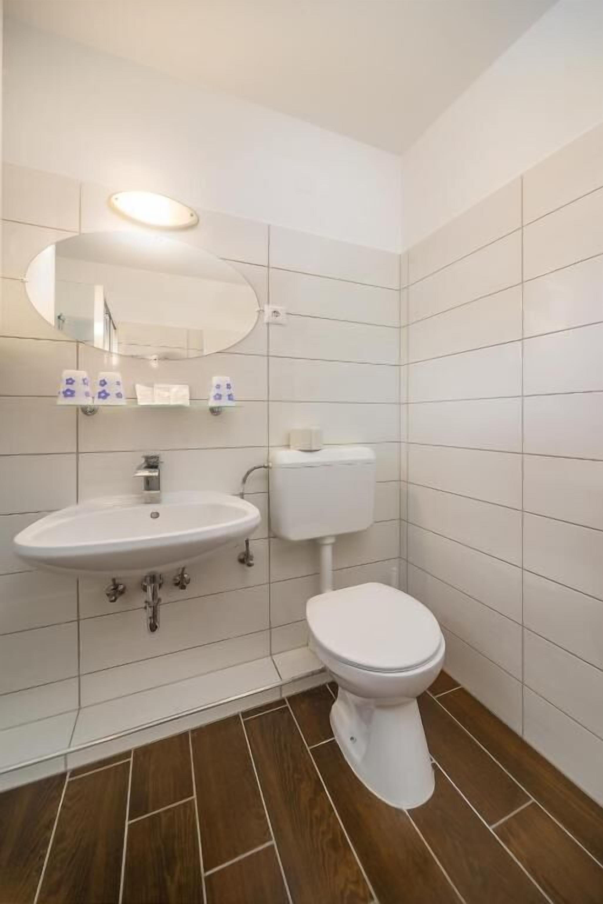 Un baño con lavabo, inodoro y espejo blancos.
