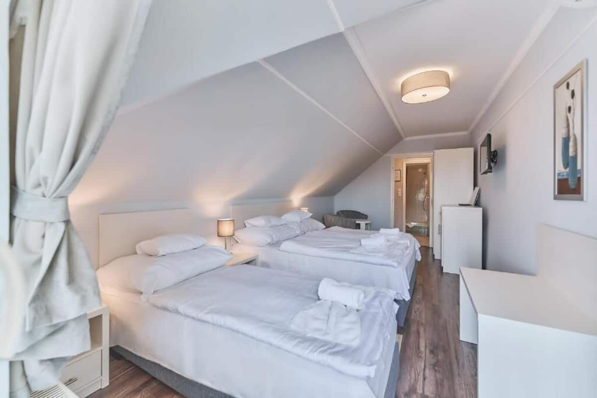 Une chambre d’hôtel avec deux lits, un bureau, une chaise et une petite kitchenette.
