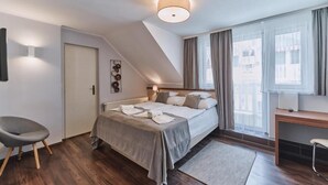 Un dormitorio con una cama, un escritorio, una silla, una puerta y una ventana.