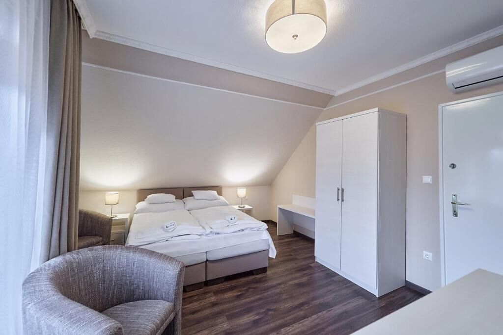 Un dormitorio con cama, una silla, armario y escritorio.