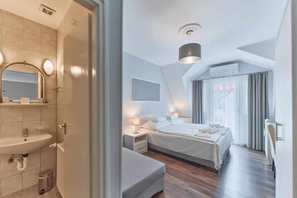 Un dormitorio moderno con una cama grande, mesitas de noche, un espejo y una ventana con cortinas.