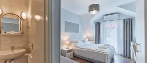 A modern bedroom with a large bed, bedside tables, a mirror, and a window with curtains.