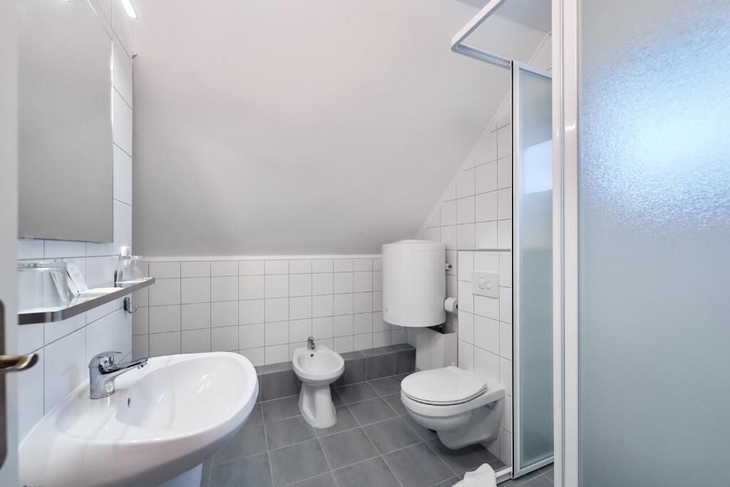 A small, modern bathroom with a sink, bidet, and toilet.
