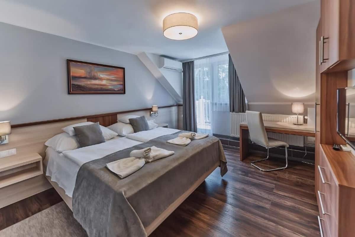 Une chambre d’hôtel moderne avec un grand lit, un bureau et une vue sur l’extérieur.