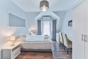 Un dormitorio moderno con cama, mesita de noche, lámpara y escritorio con sillas.