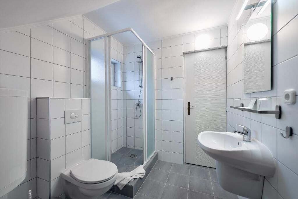 A modern bathroom with a toilet, shower, and sink.