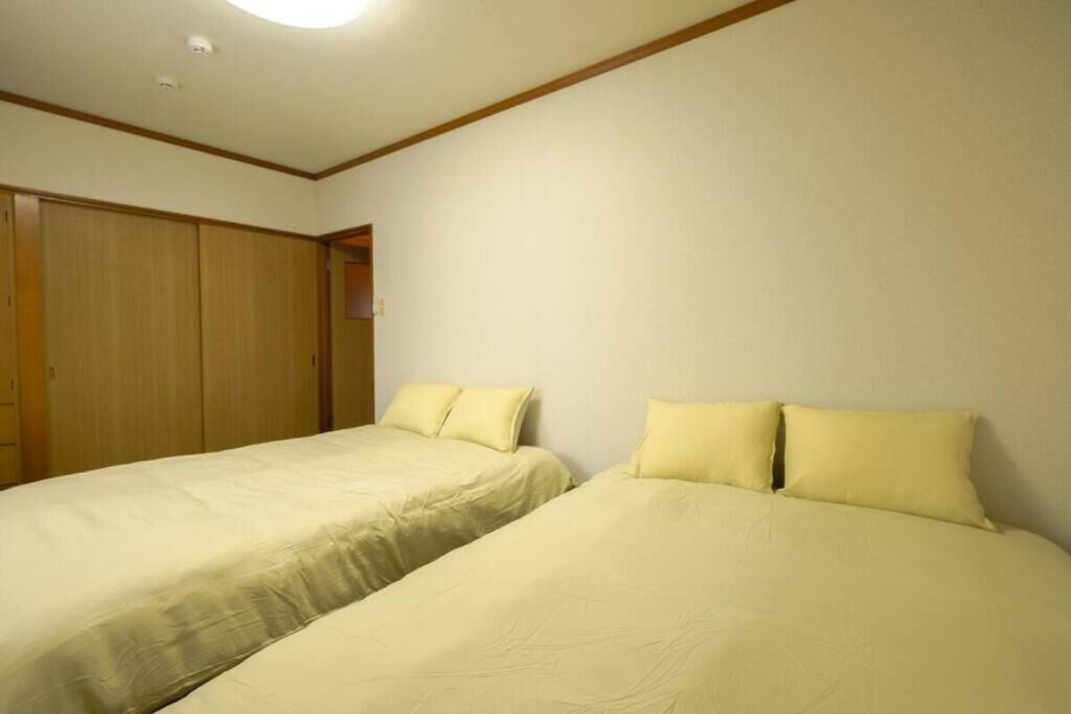 A room with two single beds, wooden wardrobes, and a white ceiling.