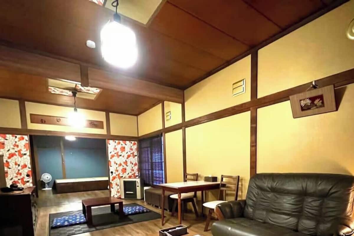 A living room with a sofa, a dining table, and a TV.