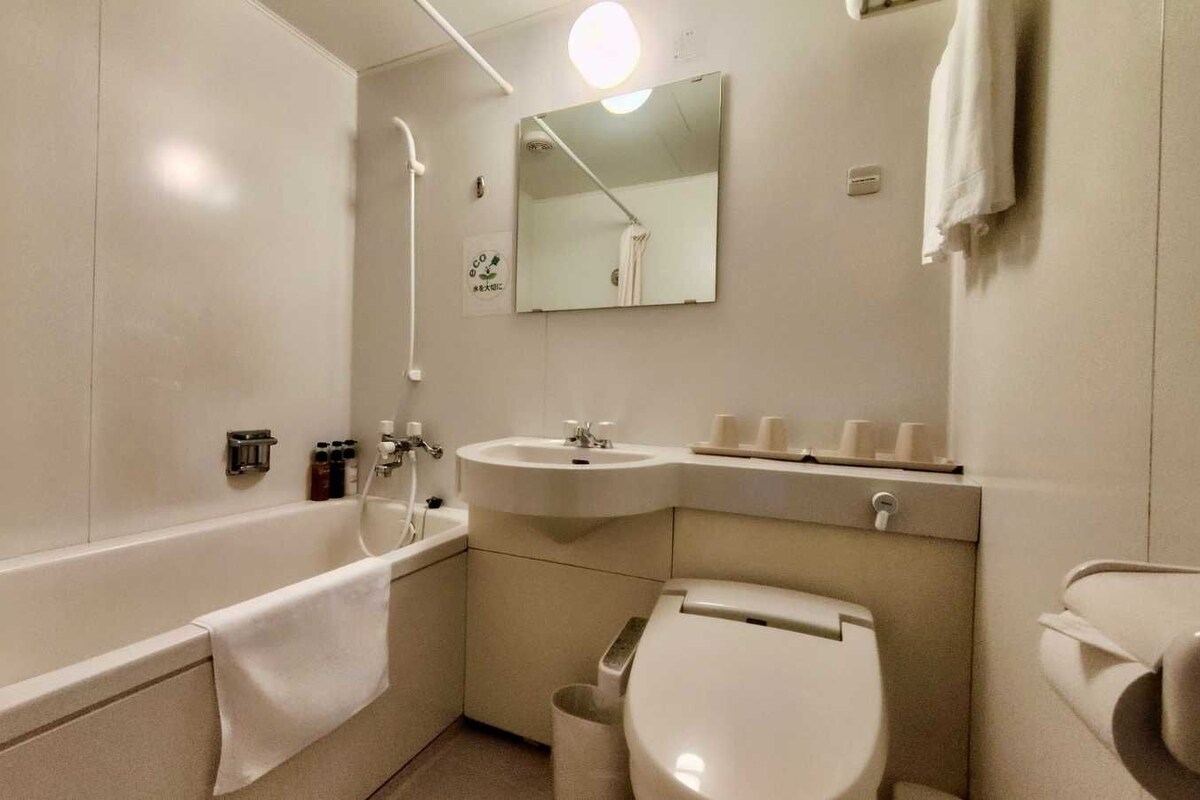 A bathroom with a bathtub, a sink, a toilet, and a mirror.
