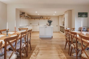 Una cocina amplia con armarios blancos, una isla central y sillas de madera con mantas de piel.