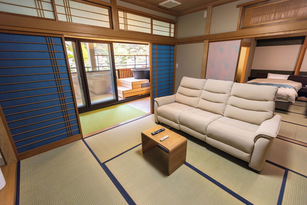 A traditional Japanese-style room with tatami flooring, a sofa, a small wooden table, and sliding doors.
