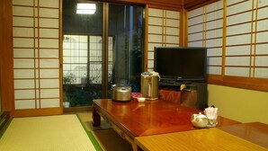 Una habitación japonesa tradicional con suelo de tatami, televisor, cocedor de arroz y un juego de té.