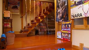 Una escalera de madera que sube a un segundo piso, una estantería llena de libros y un cartel con texto en japonés.