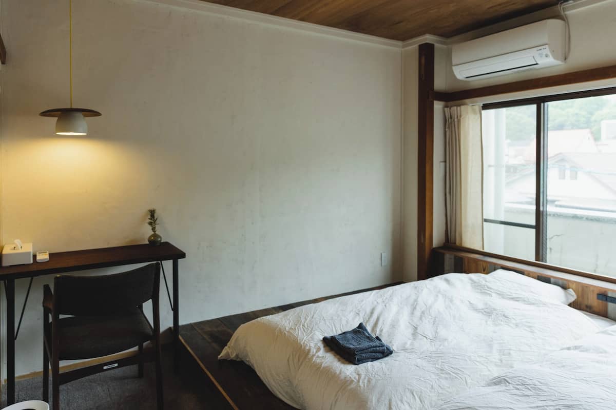 A hotel room with a bed, a desk, a chair, and a window.
