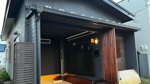 Una casa moderna con fachada oscura, terraza de madera y puerta de garaje.