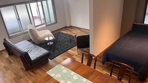 Una habitación moderna con cama, sofá, una mesita y una silla.