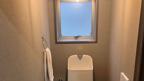 Un baño pequeño con inodoro, ventana, toallero y calentador instalado en la pared.