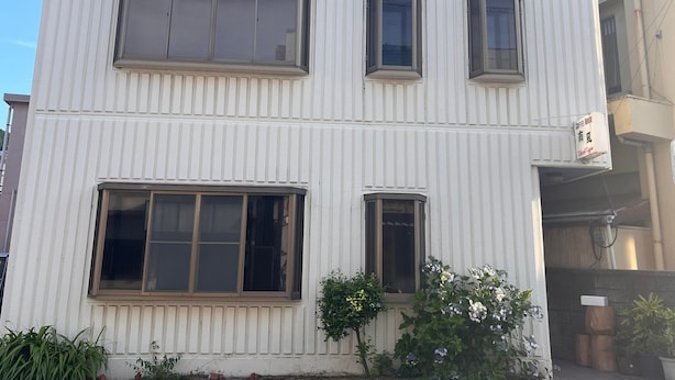 Un edificio blanco con tres ventanas en la planta baja y dos en el piso superior.