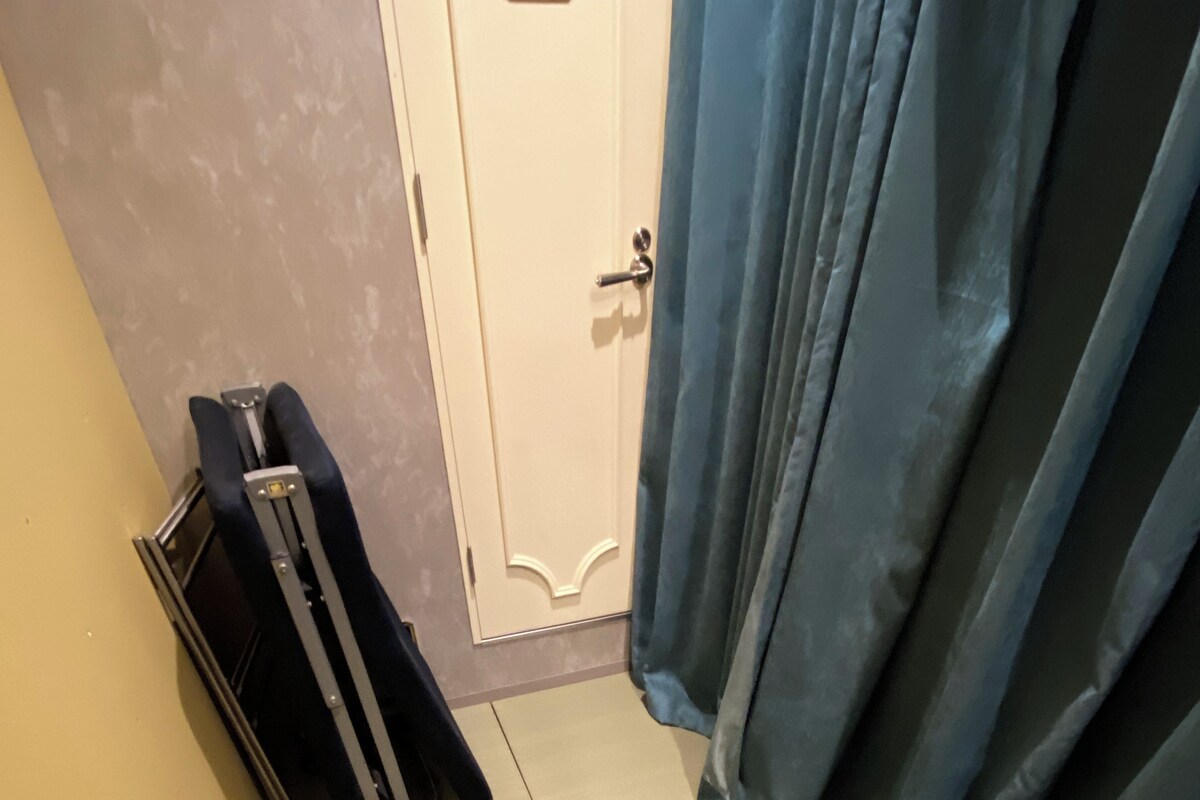 Um quarto com porta, mala e cortina.