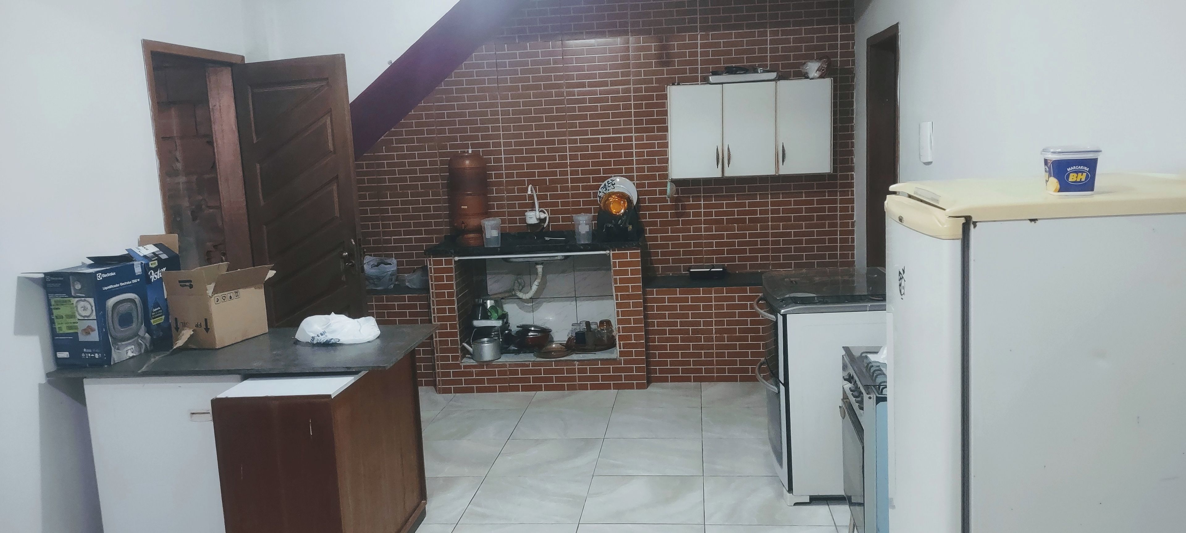 Cocina pequeña con pared de ladrillo, un refrigerador, un lavamanos y una estufa.