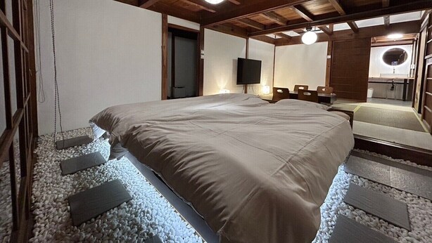 Un dormitorio con una cama grande, vigas de madera en el techo, un televisor y un espejo.