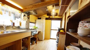 Una cocina con pisos de madera, un refrigerador, un lavamanos y un ventilador.