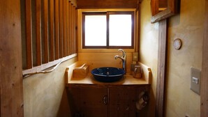 Un baño de madera con ventana, un lavabo y un espejo.