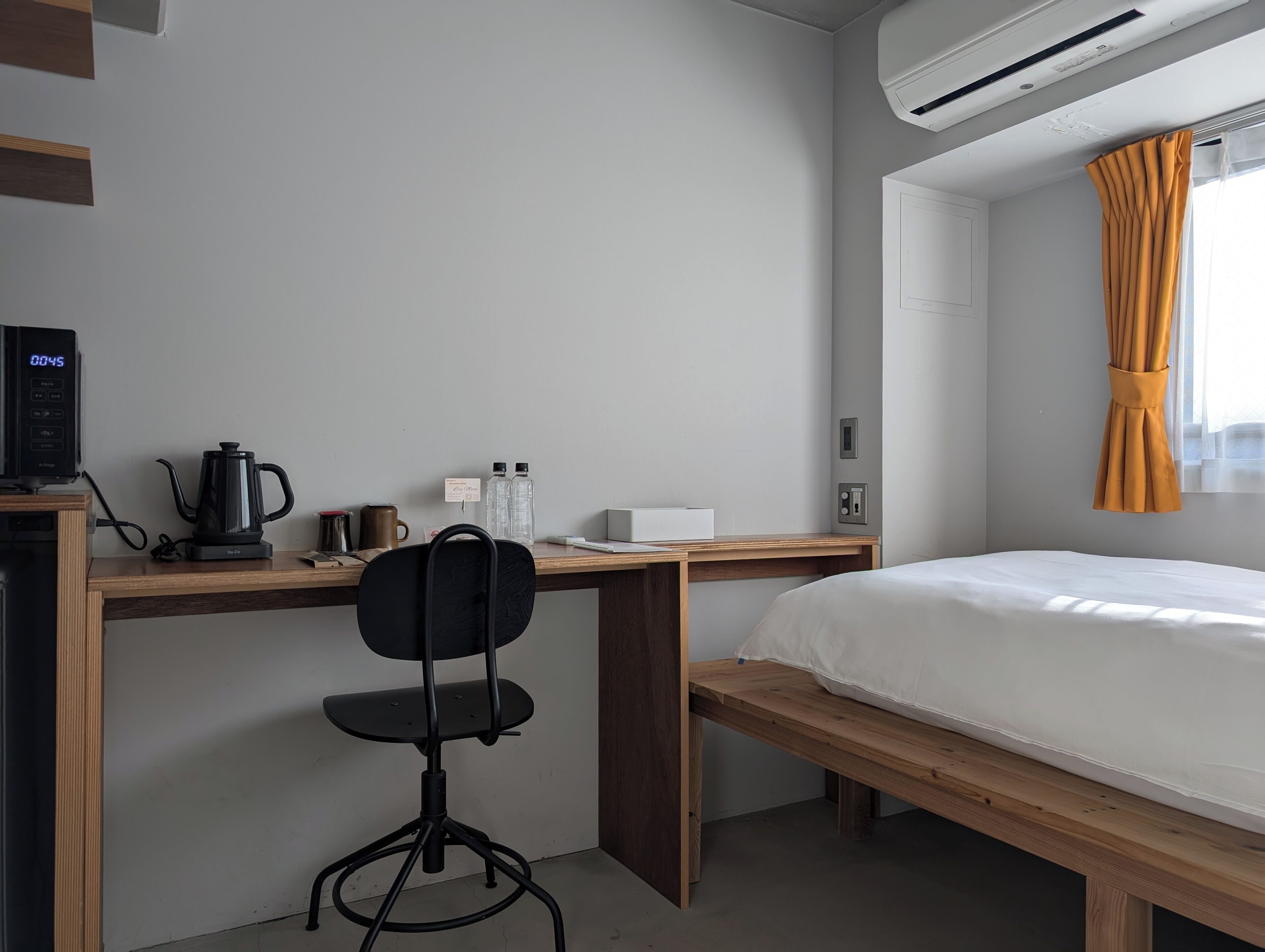 Ein Schlafzimmer mit einem Bett, einem Schreibtisch mit Stuhl, einer Kaffeemaschine und einem Wasserkocher.